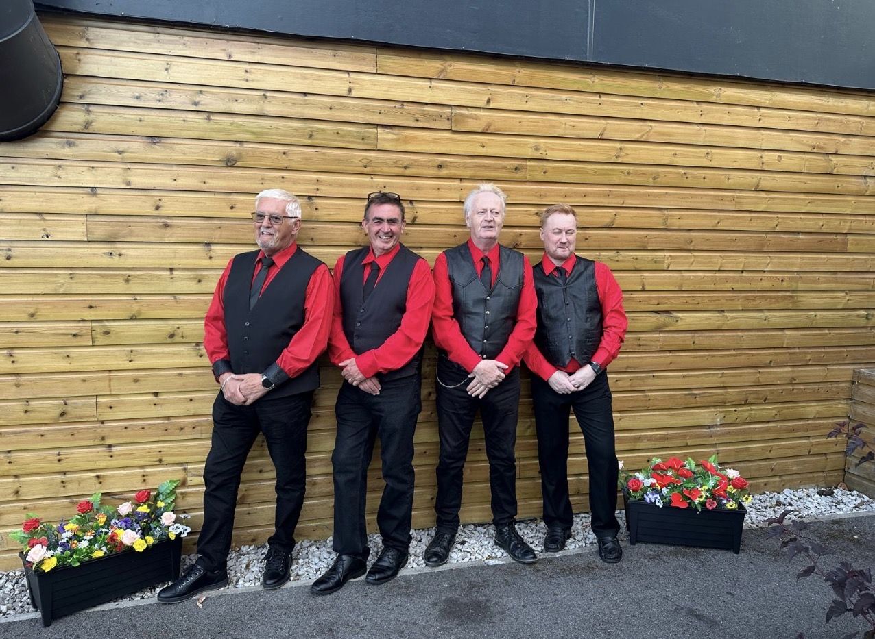 The four members of The Originals in matching red shirts, black waistcoats and ties
